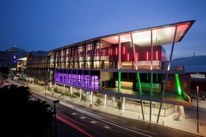 Ein modernes Gebäude mit Glasfassade und farbigem Licht.
