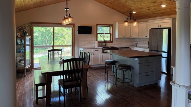 A spacious kitchen with wooden ceiling beams, white cabinets, and a large island with stools. - Spacious Seneca Lake Retreat in the Heart of the Finger Lakes! (Burdett)
