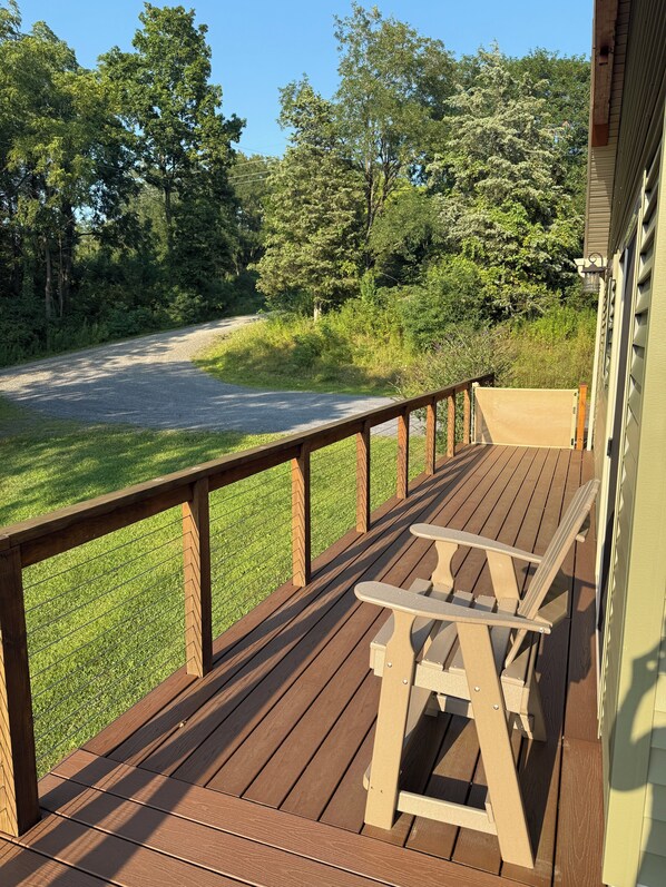 Una terraza de madera con una mesa de picnic y vistas a una carretera y árboles.