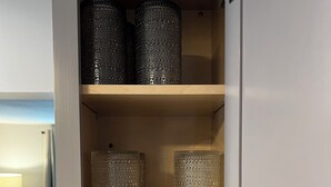 Un mueble de madera con tres estantes, cada uno con distintos objetos.