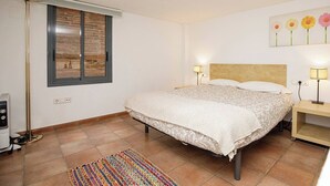 Une chambre à coucher avec un grand lit, deux lampes de chevet, une fenêtre donnant sur un beau paysage et un tapis coloré.