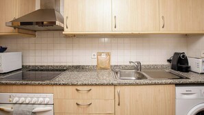 Une cuisine avec des meubles en bois, un évier en acier inoxydable, un four à micro-ondes, un grille-pain et un lave-linge.