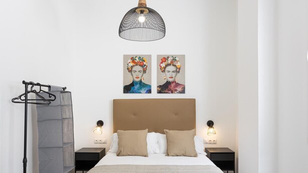 A neatly arranged bedroom with a large bed, two bedside tables, a hanging light fixture, and two wall-mounted artworks. - Picasuss Loft Close Beach & Promenade (Málaga)