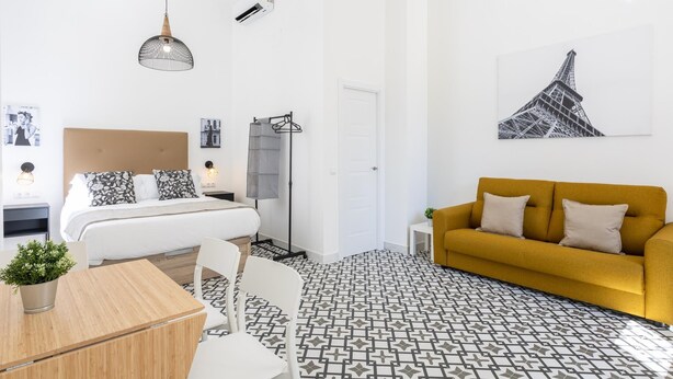 A modern bedroom with a bed, bedside table, and a yellow sofa. - Picasuss Loft Close Beach & Promenade (Málaga)