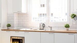 A modern kitchen with white cabinets, a stainless steel oven, a kettle, and a window with a view of buildings. - Picasuss Loft Close Beach & Promenade (Málaga)