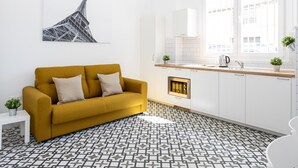 A modern kitchen with white cabinets, a yellow sofa, a patterned floor, and a large window with a city view. - Picasuss Loft Close Beach & Promenade (Málaga)