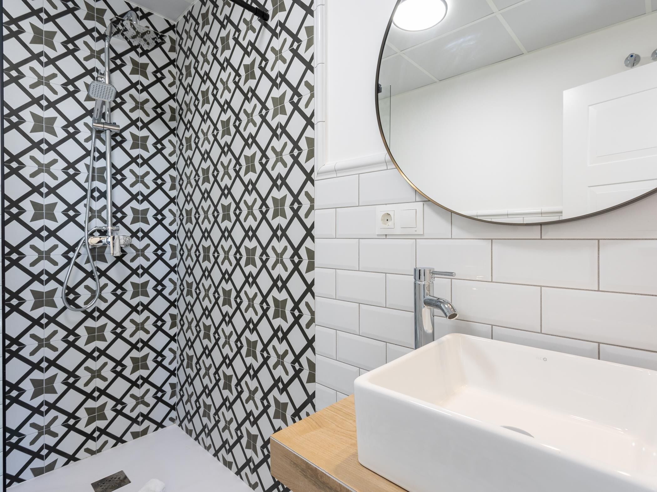 A bathroom with a shower, a sink, and a mirror.