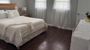 Quarto com uma cama grande, mesa de cabeceira, luminária e porta.