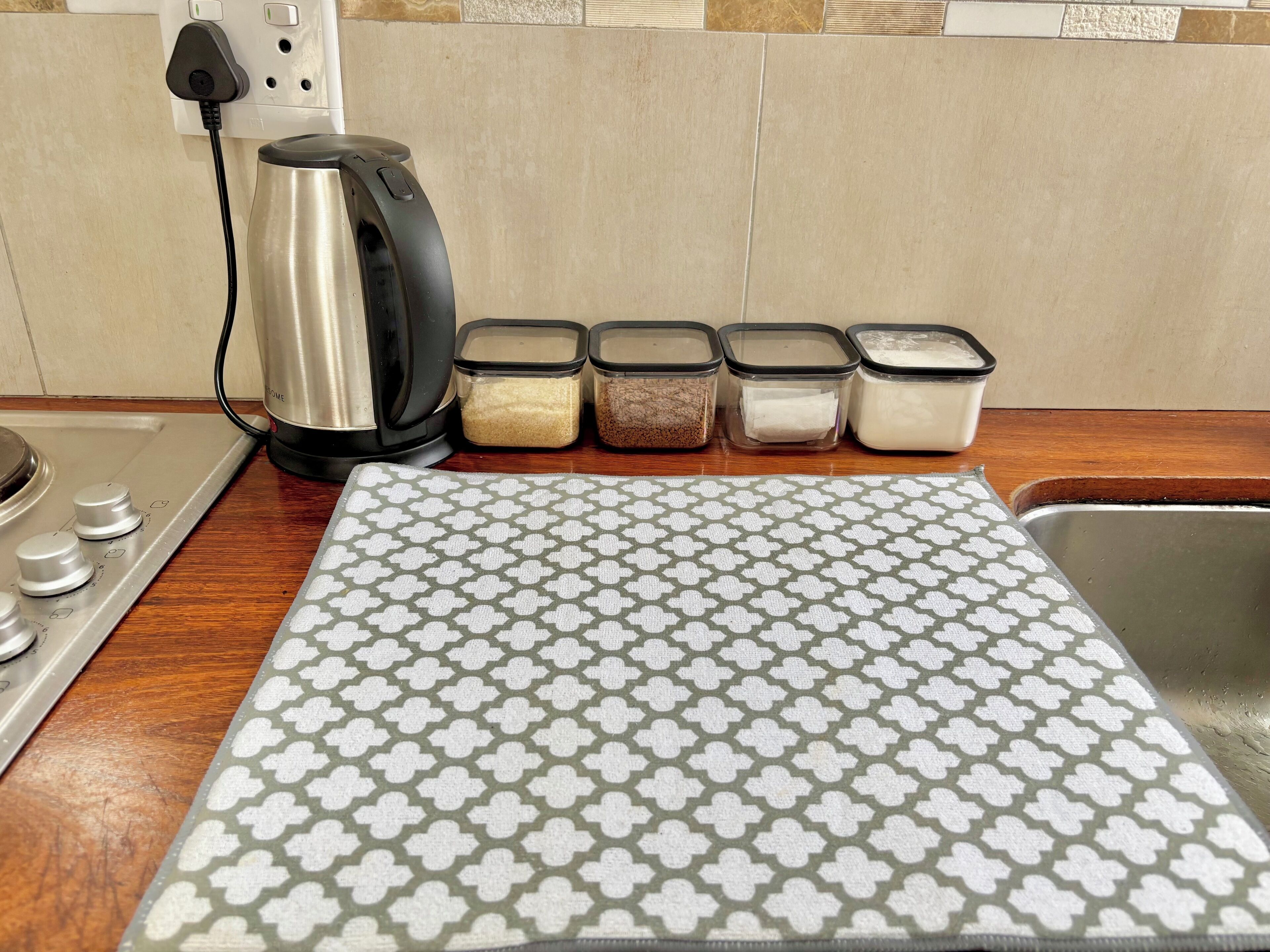 A kitchen counter with a stove, a kettle, and containers of spices.