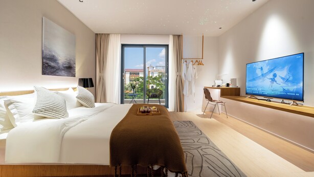 Una habitación de hotel moderna con una cama grande, televisión, escritorio y vistas al exterior.