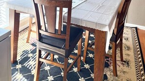 Une salle à manger avec une table dressée pour six personnes, entourée de chaises en bois, d’une nappe blanche et d’un vase rempli de fleurs.