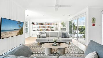 A spacious living room with a large sofa, a coffee table, and a bookshelf filled with books.