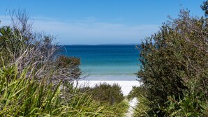 Ein Strand mit klarem, blauem Wasser, umgeben von viel Grün.