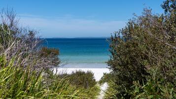 A beach with clear blue water, surrounded by greenery.