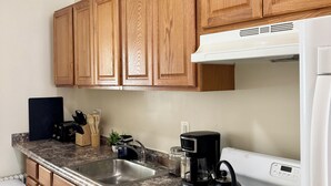 A kitchen with wooden cabinets, a granite countertop, a sink, a stove, and a coffee maker.
