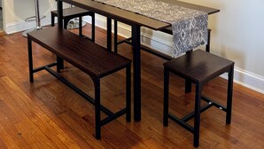 A dining area with a long table, two benches, and a patterned table runner.