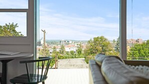 A balcony with a view of a cityscape, a sofa, and a table with chairs. - FREE PARKING, Downtown Views w/ Kitchen + Wi-Fi (Spokane)