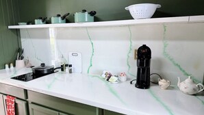 Eine Küche mit weißer Arbeitsplatte, grünen Schränken und einer Kaffeemaschine.