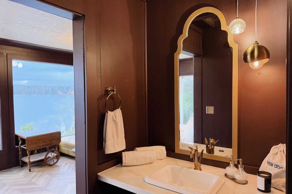 A bathroom with a large mirror, a sink, and a towel rack.