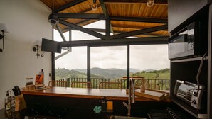 A modern kitchen with a large window overlooking a mountainous landscape.