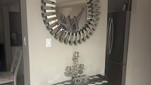 Een eethoek met een glazen tafel, metalen poten en een decoratieve spiegel aan de muur.