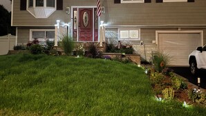 Een huis met twee verdiepingen, een rode voordeur, een Amerikaanse vlag en een garage.