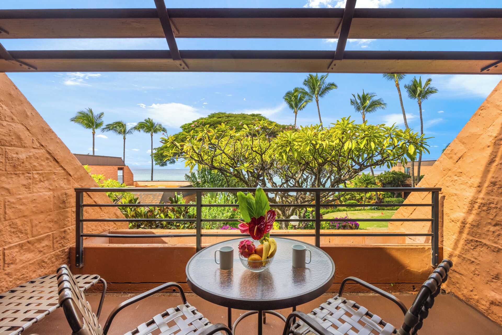 Un balcon avec une table ronde, deux chaises et un vase de fleurs.