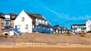 Un bâtiment situé sur la côte, doté d’un mur en pierre et avec une plage en premier plan.