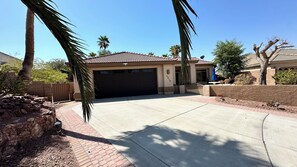 A residential property with a garage, palm trees, and a clear blue sky.