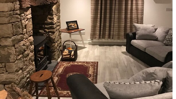 A cozy living room with a stone fireplace, a comfortable sofa, and a rug. - Lovingly restored 19th-century Bluestack Mountain farm-cottage hideaway (Letterbarrow)