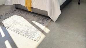 Un letto rifatto con cura, con una testiera scura, biancheria bianca e una coperta gialla.