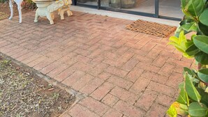 Un edificio moderno con ingresso tramite porta in vetro, un patio in mattoni con mobili da esterno e un cartello con il numero 35.