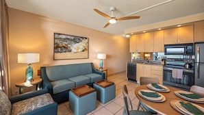 A modern living room with a sofa, coffee table, and a dining area with a table set for two. - Kuleana Club - 511 (Lahaina)