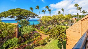 A tropical resort with a view of the ocean, palm trees, and a variety of colorful plants. - Kuleana Club - 511 (Lahaina)