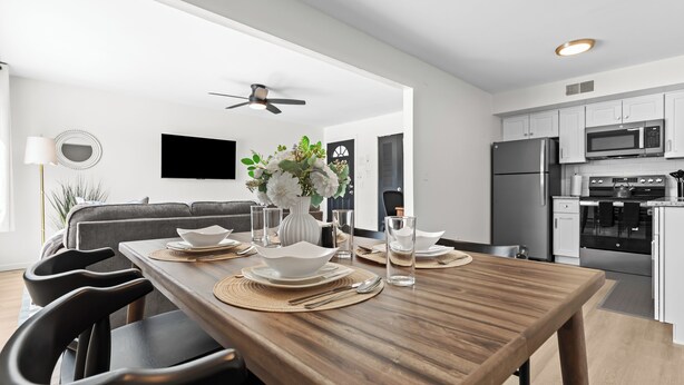 A modern kitchen with white cabinets, a stainless steel refrigerator, and a microwave.
