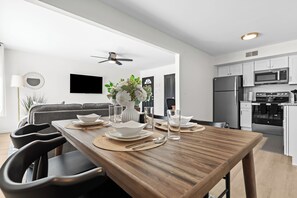 Moderni keittiö, jossa on valkoiset kaapit, ruostumattomasta teräksestä valmistettu jääkaappi ja mikroaaltouuni.