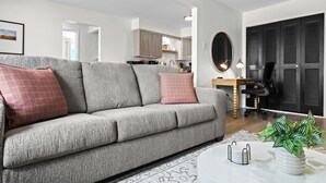 A modern living room with a grey sofa, a coffee table, and a potted plant.