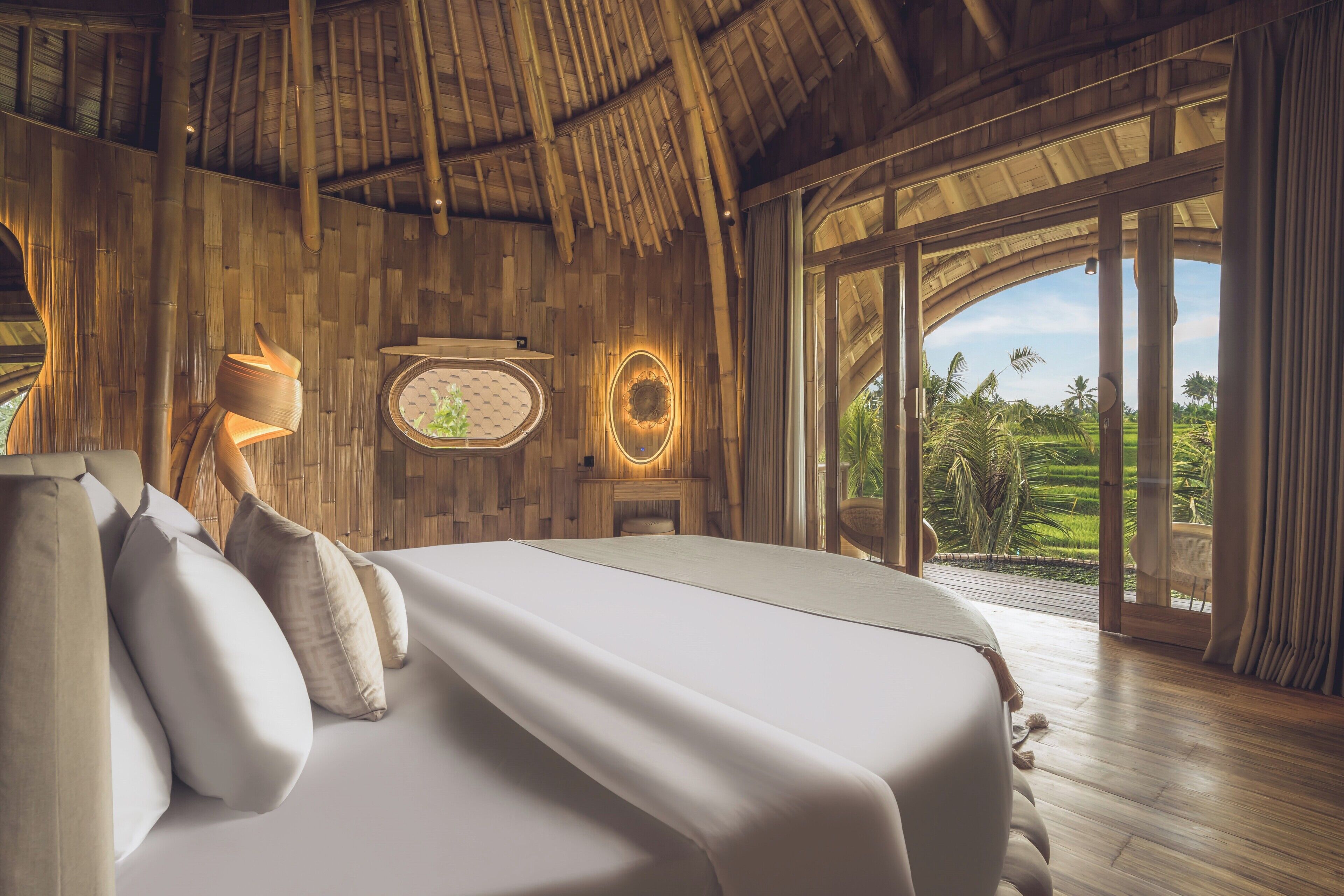 Un dormitorio espacioso con una cama grande, paredes de madera, una chimenea y vistas a un jardín exuberante.