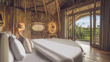 Un dormitorio espacioso con una cama grande, paredes de madera, una chimenea y vistas a un jardín exuberante.
