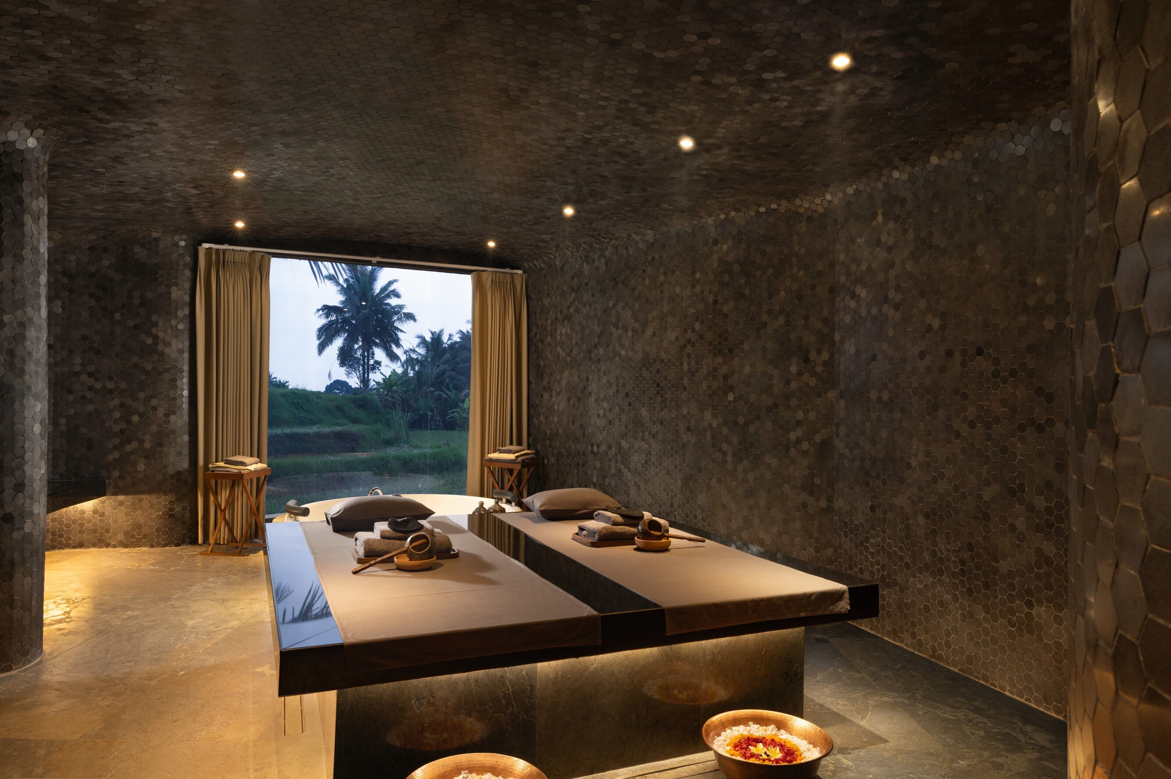 A spa room with a large massage table, a small side table, and a bowl of fruits.
