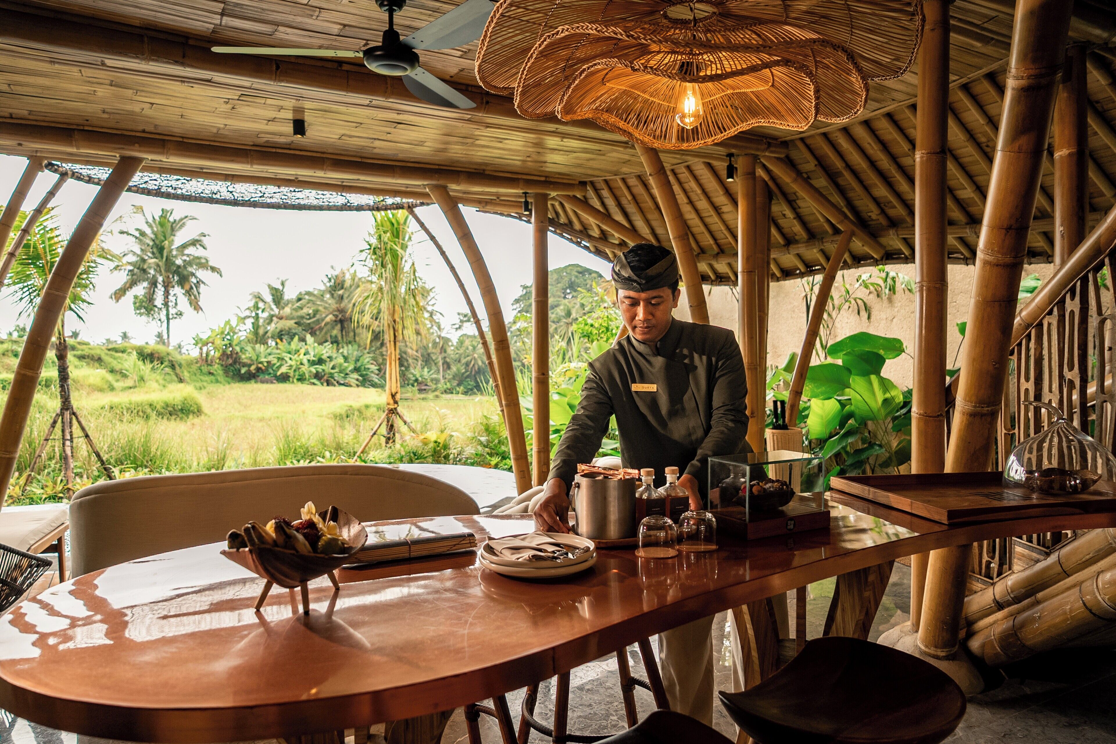 A chef preparing food at a wooden table with a view of a lush green landscape.