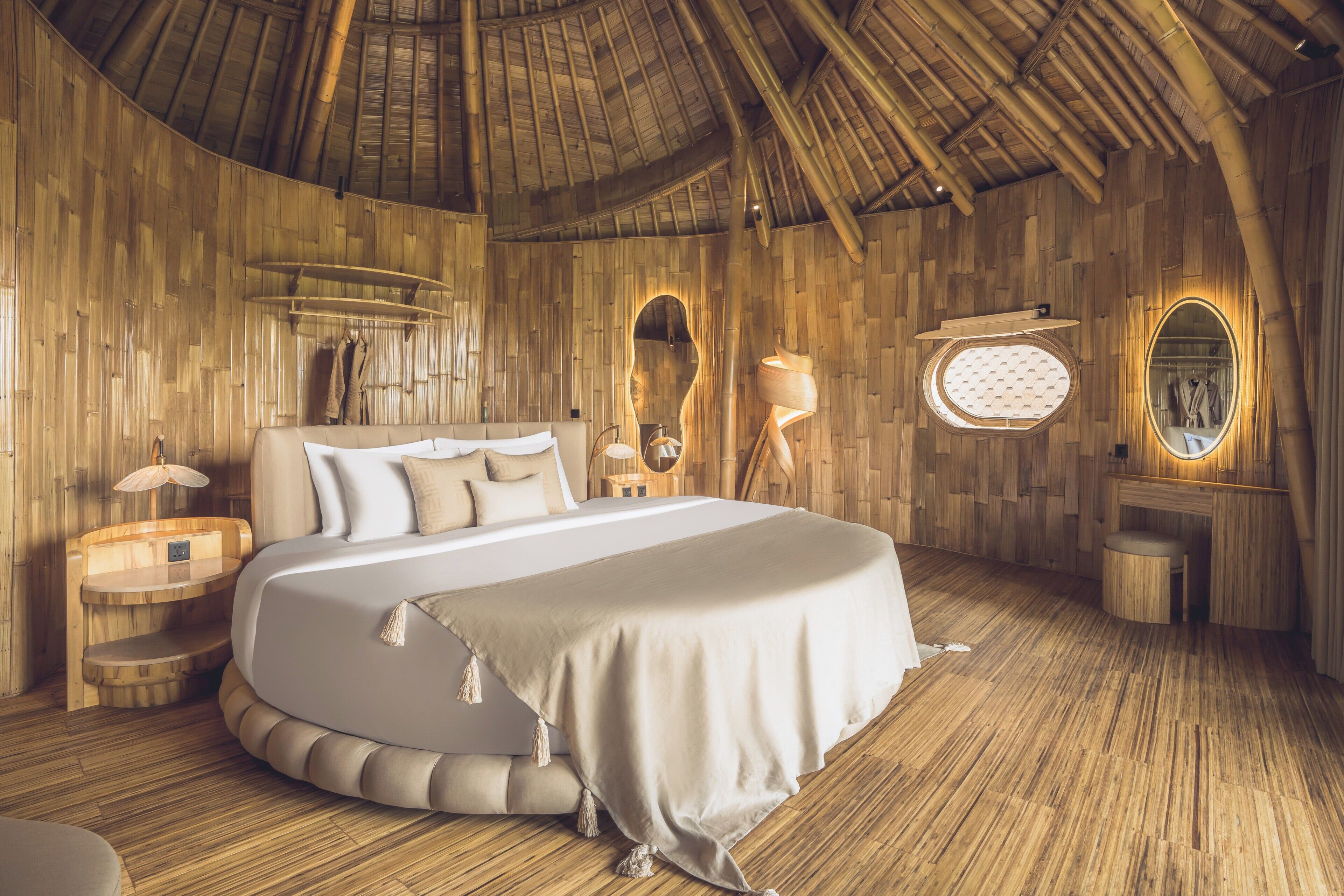 A room with a large bed, wooden walls, a curved ceiling, and a small round table.
