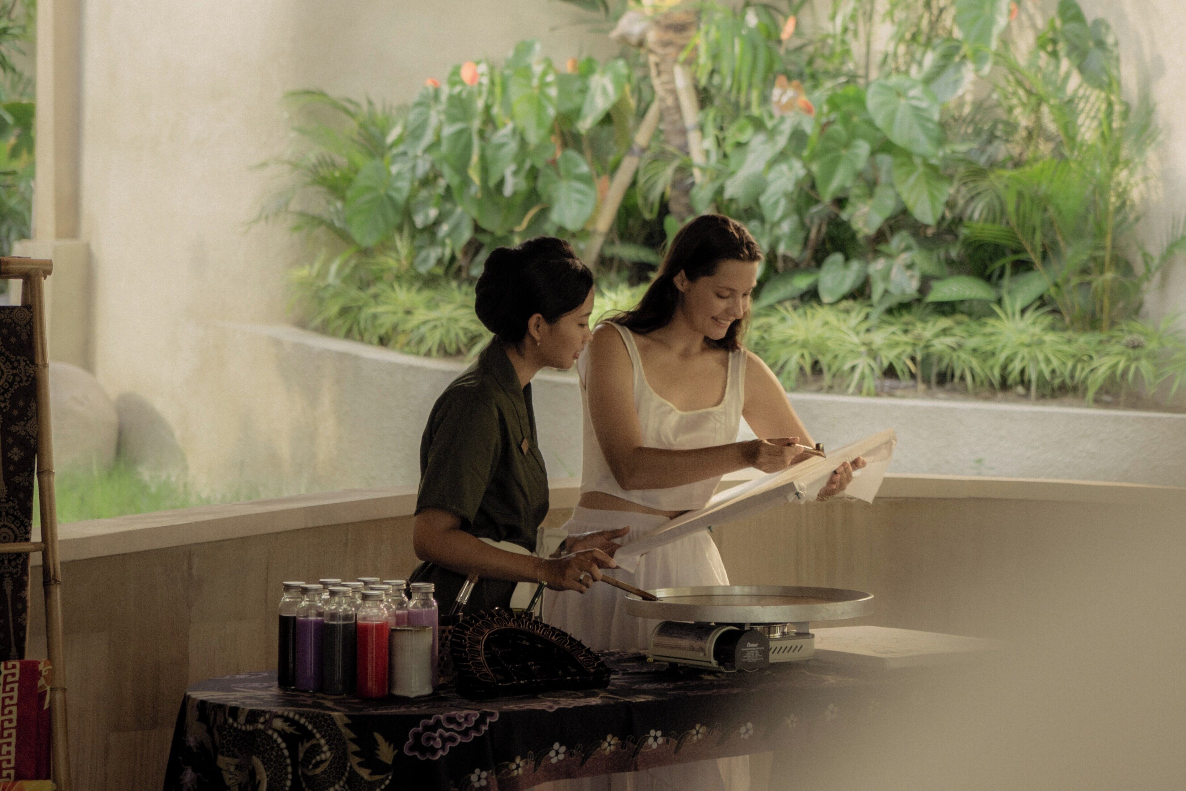 Two people cooking in a kitchen with a view of lush greenery.