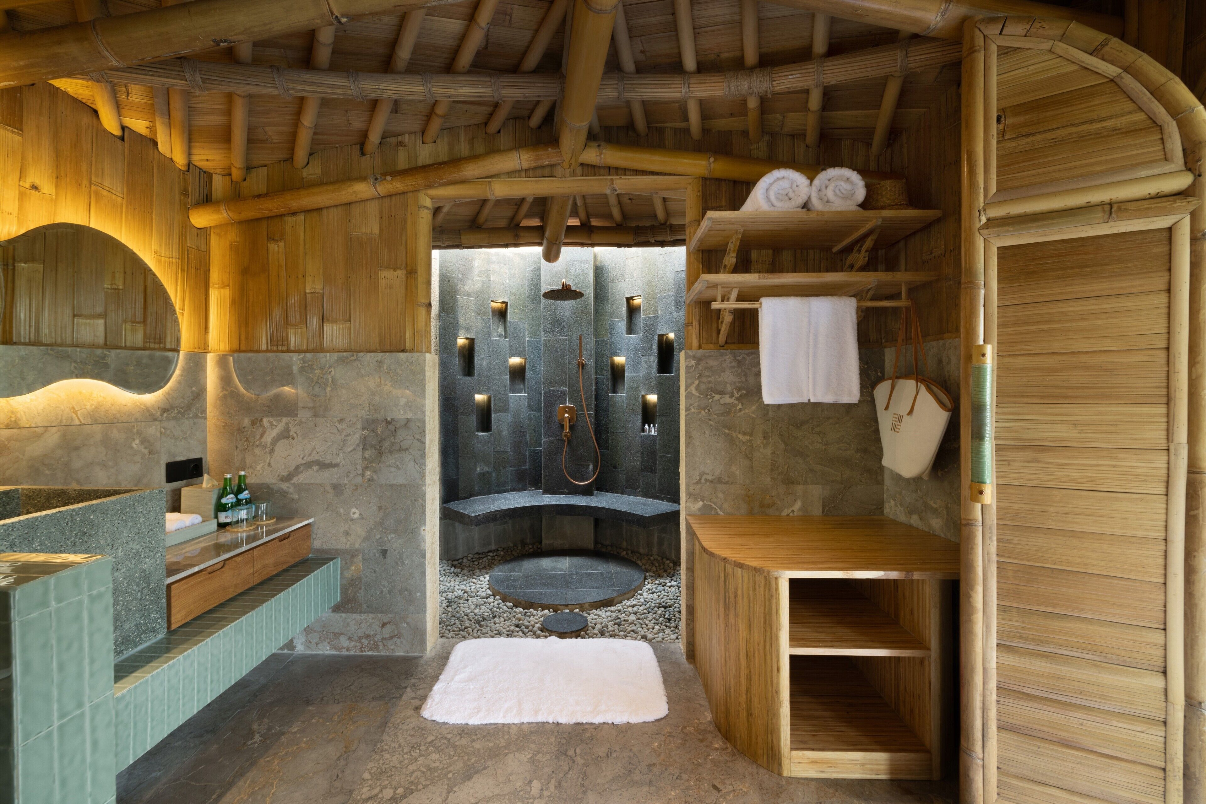 A bathroom with a stone shower, wooden shelves, a sink, and a mirror.