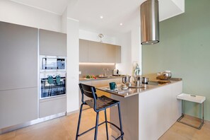 A modern kitchen with a central island, bar stools, and a built-in oven.