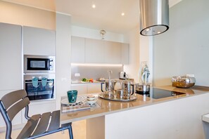 A modern kitchen with a central island, stainless steel appliances, and a pendant light.