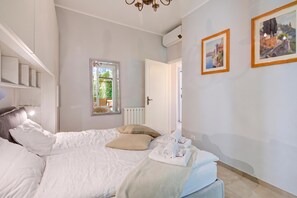 A bedroom with a bed, a mirror, a radiator, a window, and two framed pictures on the wall. - Mon Reve - Lake View Terrace and Pool, Stresa, Italy (Stresa)