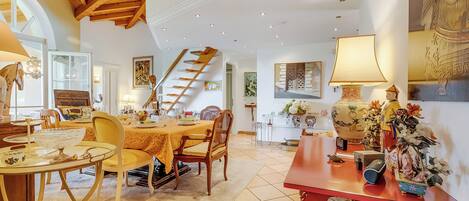 Un coin repas avec une table en bois, des chaises et un escalier.