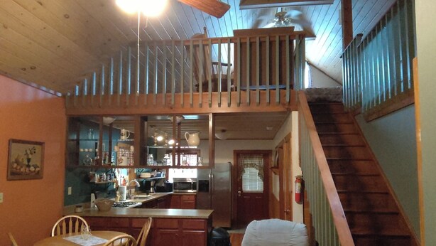 Une cuisine spacieuse avec un coin repas, un escalier en bois et une vue sur le salon.