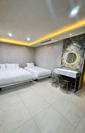 A modern bedroom with two beds, a vanity with a mirror, and a small stool.